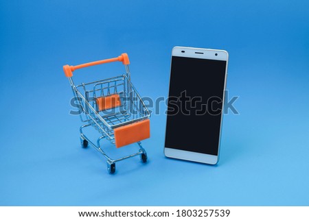 A smartphone and a trolley on blue background 