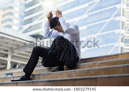 Young businessman who depresss after unemployed . He sit on the floor after fired .  A man sit on the floor in the city. He watch at the id card.