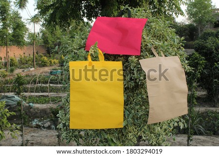 3 Colored Blank non woven eco fabric bags hanging on green plant, copy space for text and logo. Environment Concept