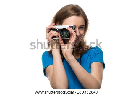 Smiling young woman photographer focusing her image as she takes a souvenir of her trip or a memorable event, isolated on white