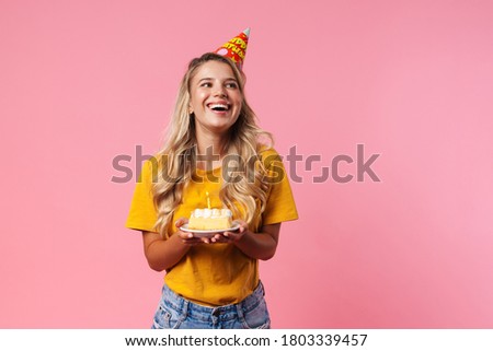 Image of happy dreaming birthday woman isolated over pink wall background holding cake with candle