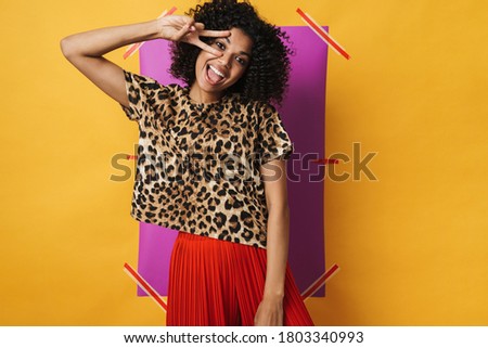 Image of funny african american woman laughing and showing peace sign isolated over multicolored background