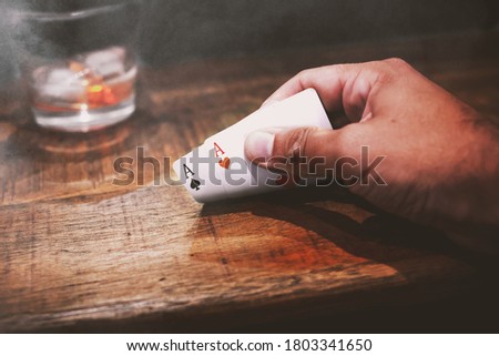 Poker player holding two aces in a smoky place