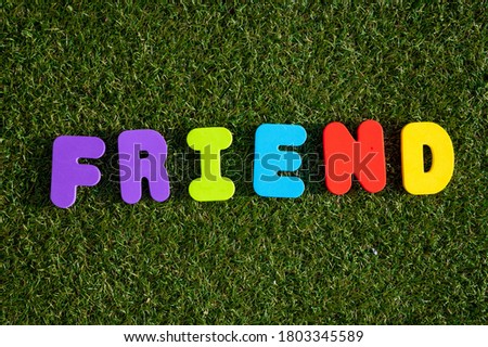 Capital letter "Friend" word from colorful of wood on grass background.