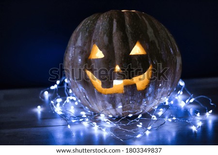 Halloween pumpkin on the table with lights all around, black background, in the spotlight.