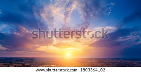 Rural landscape in the evening with beautiful burning sky, aerial view. Panoramic view of countryside during blazing sunset. Panorama from 21 pictures