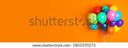 Bunch of bright balloons on orange background, space for text. Banner design 