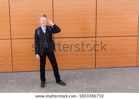 the cheerful schoolboy in a suit on the street