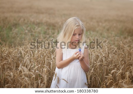 Cute little girl walks on a field of wheat in summer. Happiness, joy, fun, laughter.