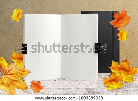 Notebook mockup on wooden background with autumn leaves 