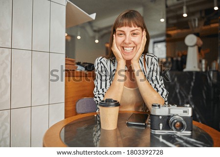 A front view of smiling young woman photographer who is enjoying herself while waiting for somebody outdoor
