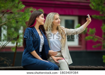 two beautiful young women in suits with a phone
