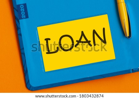 The word LOAN is written in black marker on the yellow paper for notes. text writing Loan. Concept meaning Credit Mortgage Financial Assistance Cash Advances Debt.