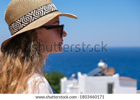 Beautiful young woman in white dress sunglasses and bikini straw hat looking at sea view in resort hotel villa