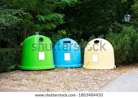 three large bins for segregation of garbage with blank banners for inscriptions. Baskets for segregation in a green park.