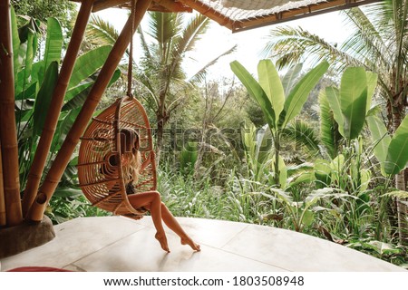 Tourist woman swing on wicker rattan hang chair in the jungle, nature view Royalty-Free Stock Photo #1803508948