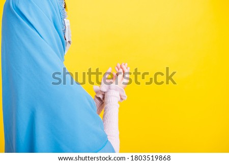 Asian Muslim Arab, Portrait beautiful young woman religious wear veil hijab and face mask protect to prevent coronavirus she henna decorated hands praying to Allah God, isolated on yellow background
