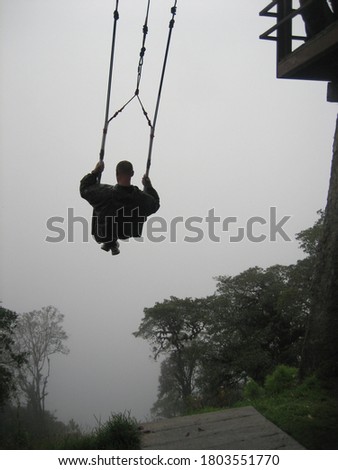 The concept of fear of the unknown. A man on a swing is flying into a foggy void.