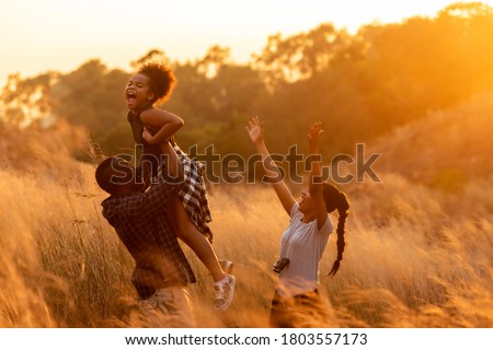 Happy African family father mother and child daughter travel and running on meadow nature on silhouette lights sunset.  Travel and Family Concept
