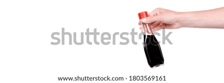 Hand with soy sauce in glass bottle with red cup. Isolated on white background, copy space template, banner.