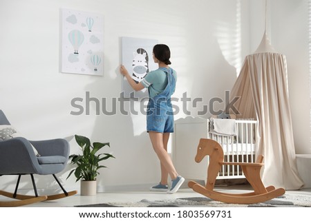 Decorator hanging picture on white wall. Children's room interior design