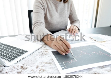 The hands of a female business brokerage are planning business investments by analyzing and calculating the stock market to find market profits.