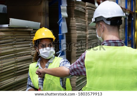 Warehouse workers wearing face mask have a greeting by touching the elbow or elbow bump to prevent covid 19 infection in warehouse.