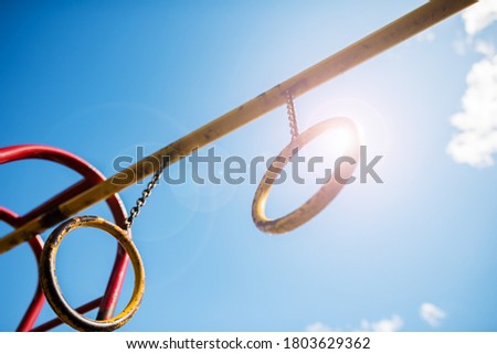 Children entertainment Playground for sports with rings with a metal chain for gymnastics against the sky.