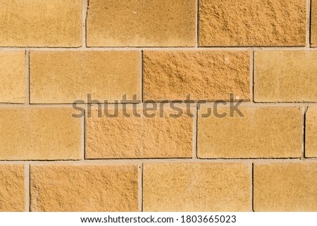 The close up view of big yellow blocks in the building wall. There is place for text. The background is unfocused with art noise. 