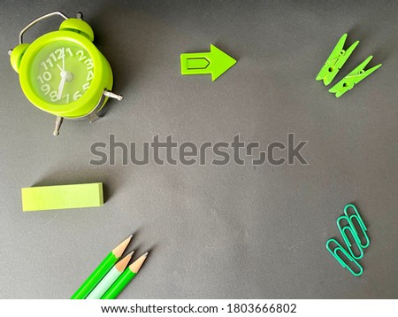 Green pencils, clock and arrow sign and black background