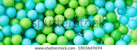 Green and blue eatable sugar pearls for food decoration. Panoramic image