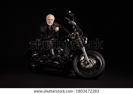 Portrait of his he nice attractive content serious grey-haired dude hipster traveler sitting on chopper spending weekend exploring world tour trip insurance isolated black color background Royalty-Free Stock Photo #1803672283