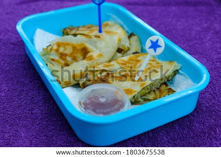 Selective focus picture of "murtabak" in breakfast pack by a wife for her husband. Murtabak is a stuffed pancake or pan-fried bread which is commonly found in the Arabian Peninsula and Southeast Asia.
