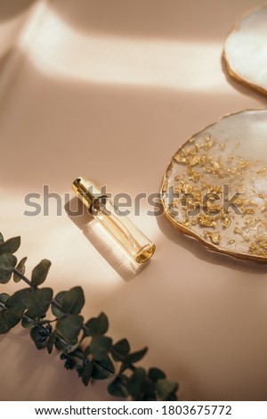 Small perfume bottle on warm pastel and golden colors table. Commercial, brand packaging mockup. Copy space. Refillable travel size. Product photography