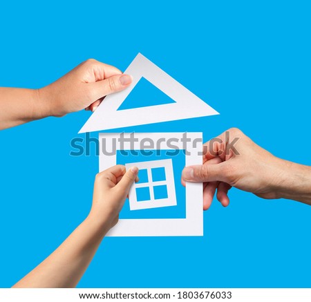 Hands of family holding a model of paper house. Idea of planning to have a home.
