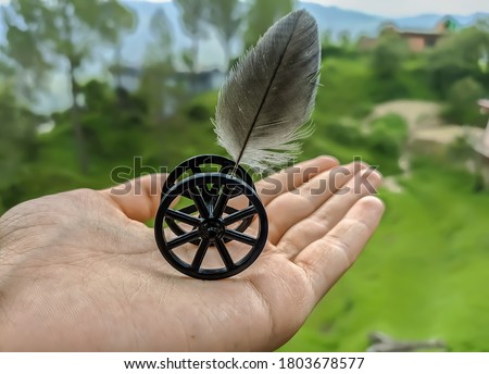 uttarakhand,india:wheel and feather.this is a picture of a wheel and feather in hand.the hand is holding the wheel and feather setup.wheel with bird feather on hand.wallpaper.