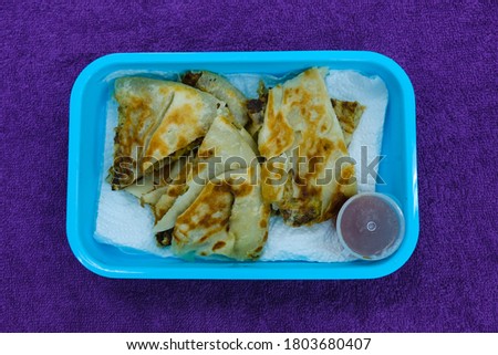 Flatlay selective focus picture of "murtabak" in breakfast pack. Murtabak is a stuffed pancake or pan-fried bread which is commonly found in the Arabian Peninsula and Southeast Asia.