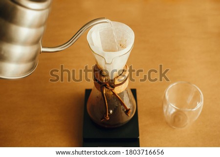 Alternative coffee brewing . Barista making filter coffee on brown background. Pouring hot water from steel kettle in filter with ground coffee in pour over on scale. Royalty-Free Stock Photo #1803716656