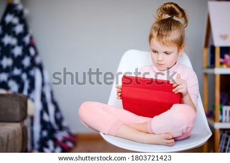 Distance learning online education, young caucasian schoolgirl with tablet laptop doing school homework, child watching cartoons in a digital tablet at home