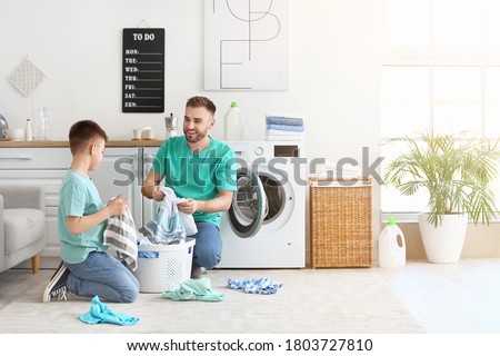 Man and his little son doing laundry at home Royalty-Free Stock Photo #1803727810