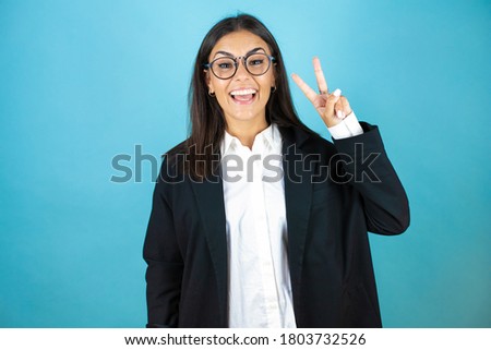 Young beautiful business woman over isolated blue background showing and pointing up with fingers number two while smiling confident and happy