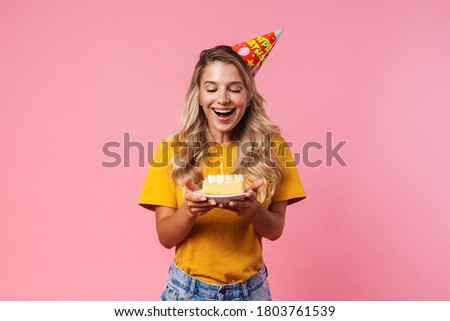 Image of happy cheery birthday woman isolated over pink wall background holding cake with candle