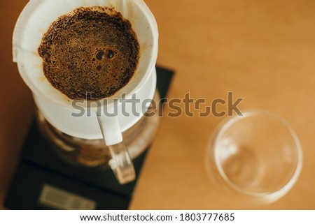 Brewing aromatic fresh coffee in paper filter closeup in pour over on scale. Alternative coffee brewing closeup. Barista making filter coffee on brown background Royalty-Free Stock Photo #1803777685