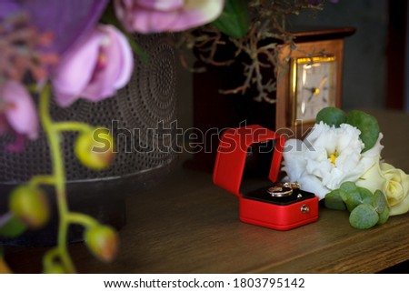 wedding rings in a red box on the table with flowers
