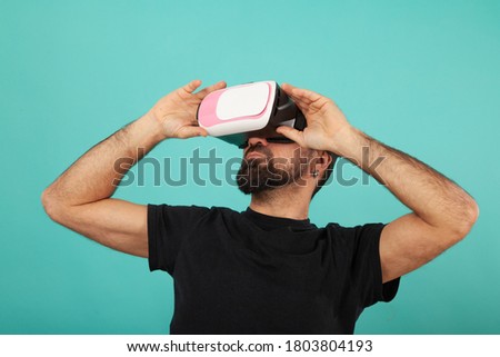 Bearded man use virtual reality glasses, goggles. Guy in VR headset is looking at interactive screen. Playing mobile game app on device.