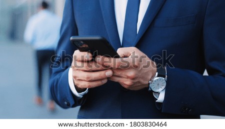 Close up image of business man hands holding and using smartphone.