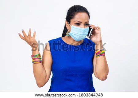 Pretty Indian female wearing Covid-19 protection mask. Indian woman clicks a selfie with her phone. Woman with expressive face.
