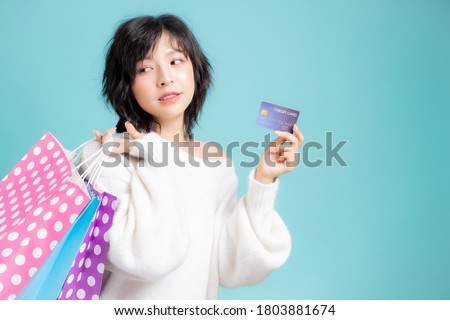 Woman holding many shopping bags and credit card, isolated on blue studio background