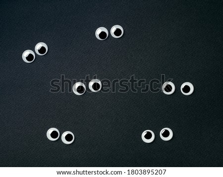 six pair of googly eyes on black background. Top view or flat lay. Plastic toy eyes on dark or balck background - halloween concept