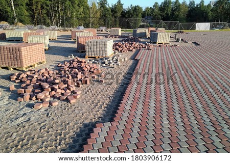 Red and grey paving stones, cement tiles for road construction, paving slabs on wooden pallets on the construction site. Horizontal photo Royalty-Free Stock Photo #1803906172